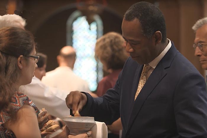 A man in a suit takes communion.