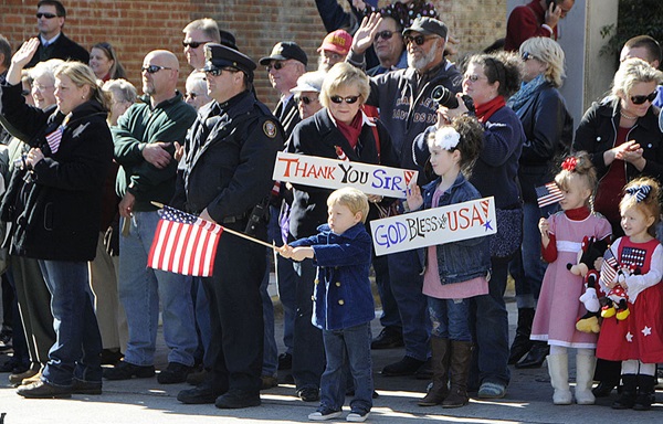 Veterans-Day-Parade-1063x68 An American boy waves a U.S. flag during a Veterans Day parade. Public domain photograph from defenseimagery.mil.