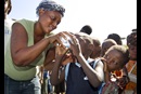 Sharlene Jean offers a sample of treated drinking water to a child living in a makeshift camp in Gresier, Haiti. The United Methodist Committee on Relief and partner agencies provided water treatment supplies to the camp. Photo by Mike DuBose, UMNS.
