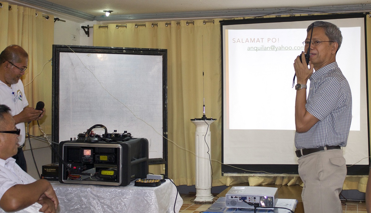The Rev. Jose Umali (right) tries ham radio equipment during a lecture to clergy and laity in the Philippines. Photo courtesy of Gladys Mangiduyos
