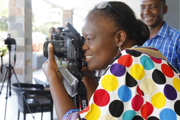 Photo by Kathleen Barry, UMNS  Betty Kazadi Musau focuses her camera during training for communicators from the Congo Central Conference. United Methodist Communications held the training Nov. 12-17 in Ndola, Zambia.