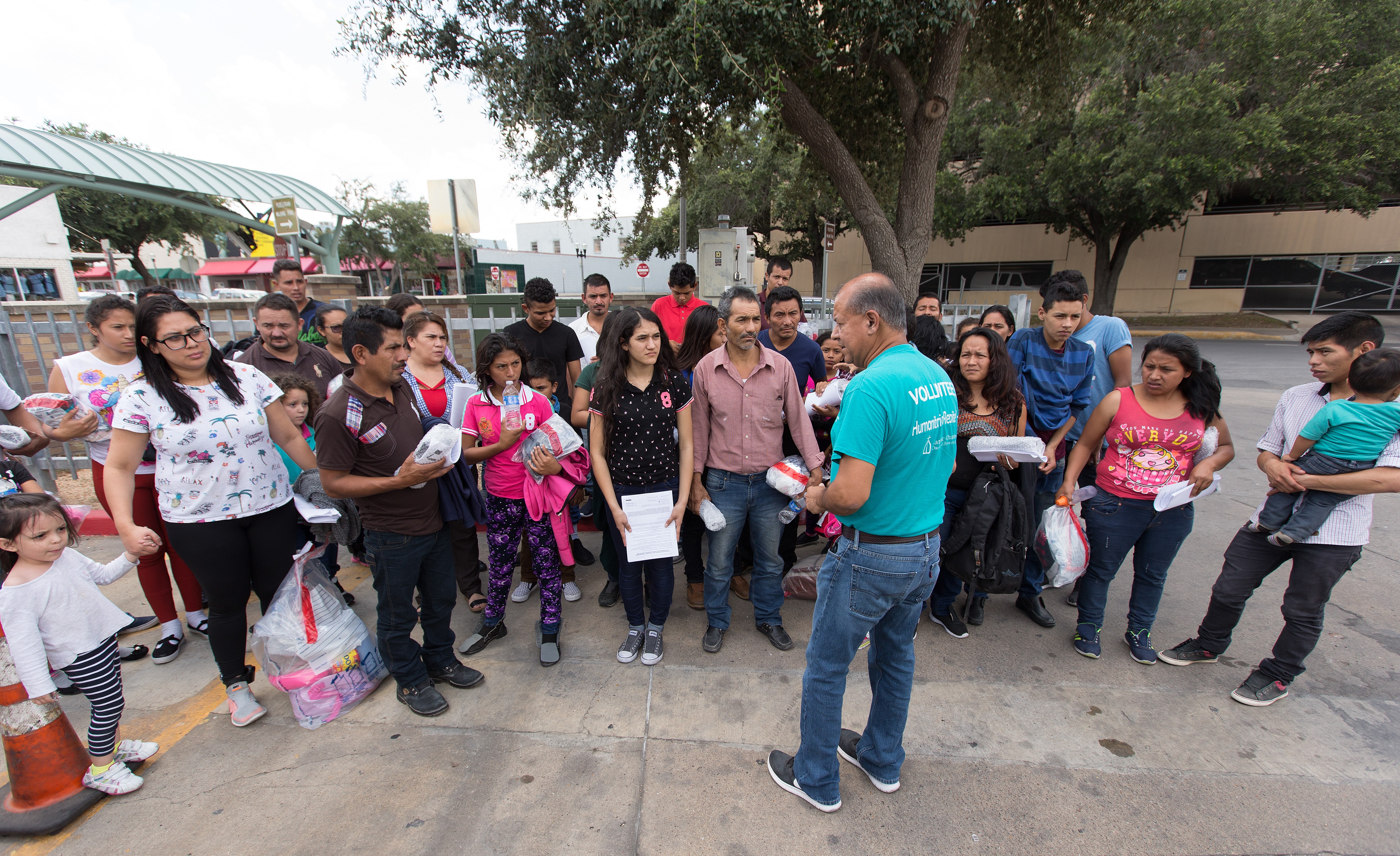 Eli Fernandez (front, in blue t-shirt), a volunteer with Catholic Charities, helps direct immigrants who have been released from detention by the U.S. Border Patrol and brought to the bus station in McAllen, Texas. Photo by Mike DuBose, UMNS. 