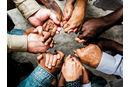 A diverse group of people stand in a circle holding hands. Image by Rawpixel, iStockphoto.com.