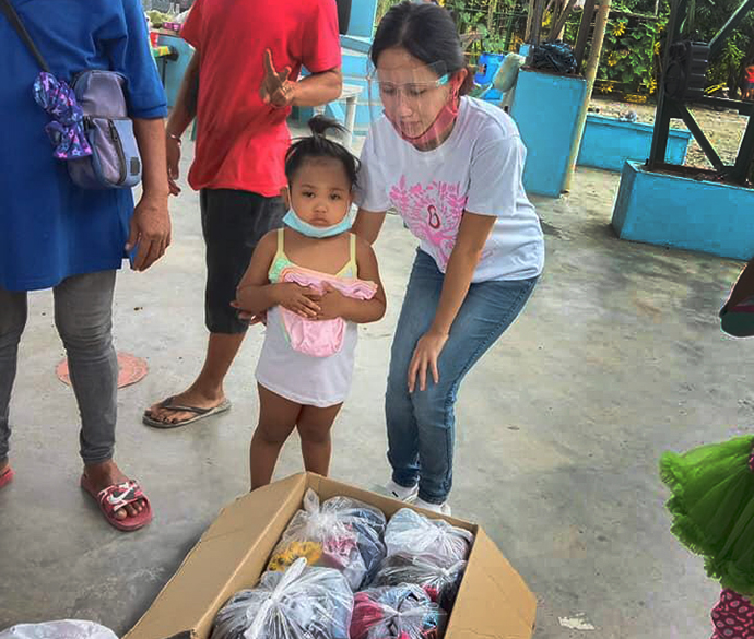 Jazel Resurreccion Lustre, a volunteer teacher in Bulacan province, helps a child from the Longos neighborhood, which was devastated by fire. The September blaze destroyed 28 of 108 homes in the impoverished community. Photo by Emily Sison. 