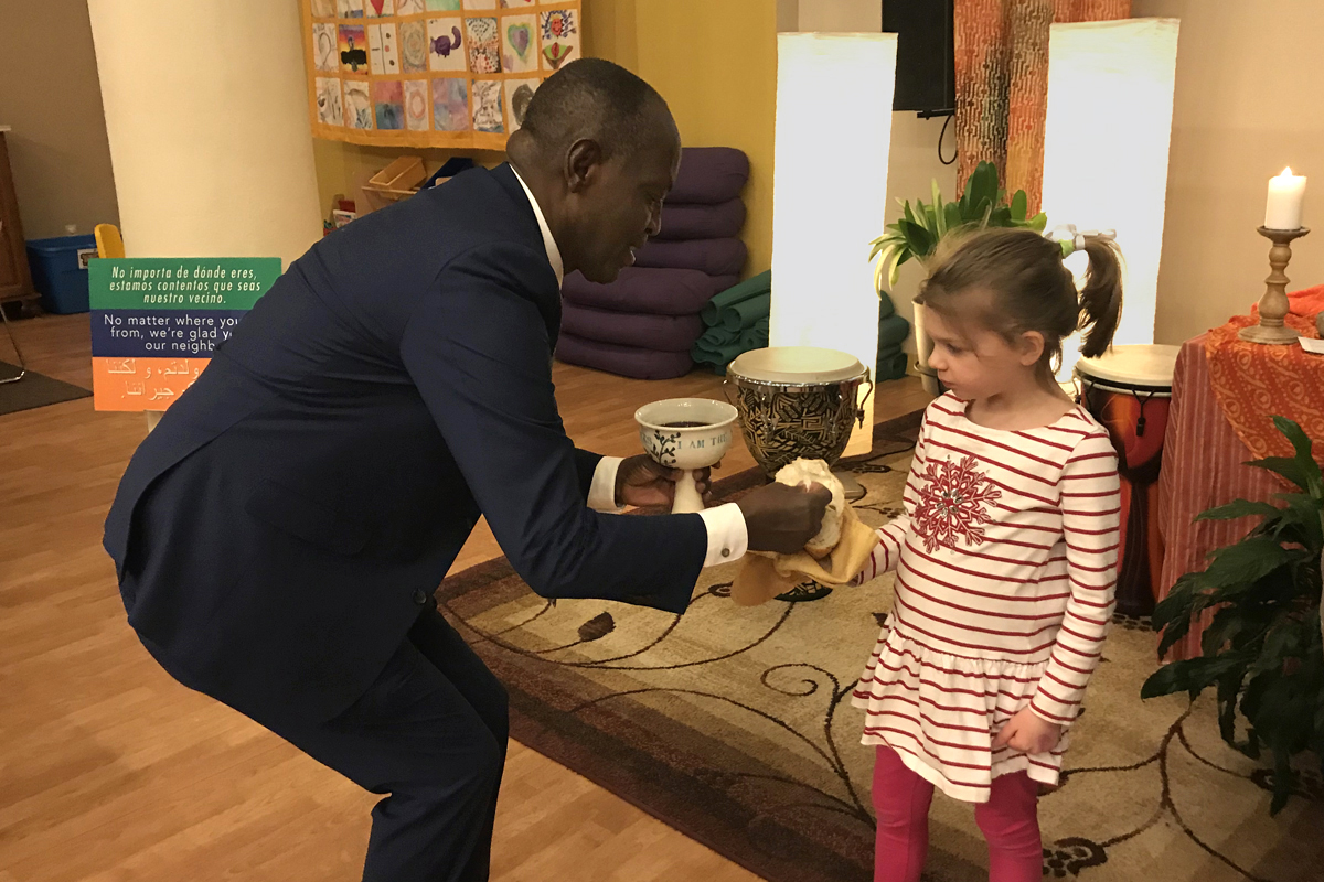 The Rev. Nathan Ndayiziga, a Methodist pastor from Burundi, gives communion to Emilia Lovejoy during a 2019 service at HopeGateWay Church in Portland, Maine. The church is among multiple congregations in the process of disaffiliating from The United Methodist Church. HopeGateWay is doing so in solidarity with LGBTQ members. Photo courtesy of the Rev. Sara Ewing-Merrill. 