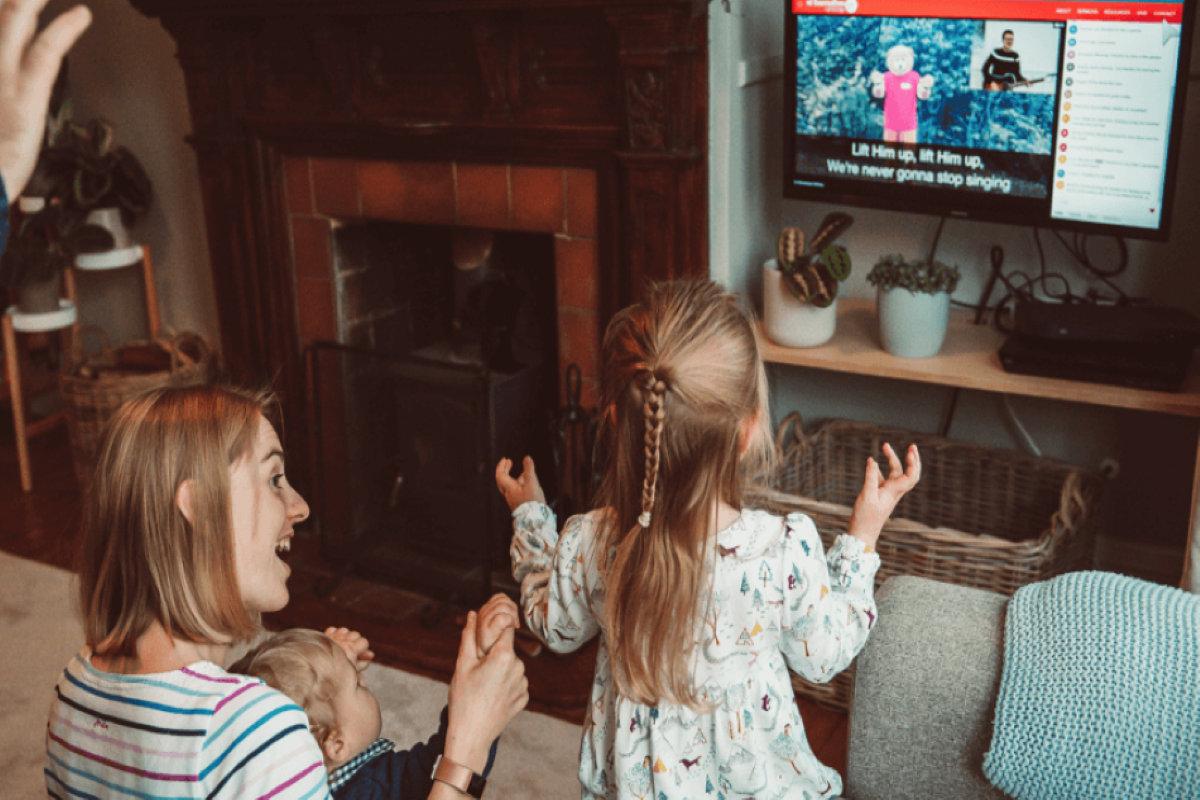 Family clapping and interacting with online worship from their living room. Courtesy of the Lewis Center for Church Leadership.
