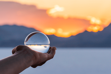 Hand holding a crystal globe with sunset in background. Image by krblokhin, iStockPhoto.com. Image courtesy of the Connectional Table.