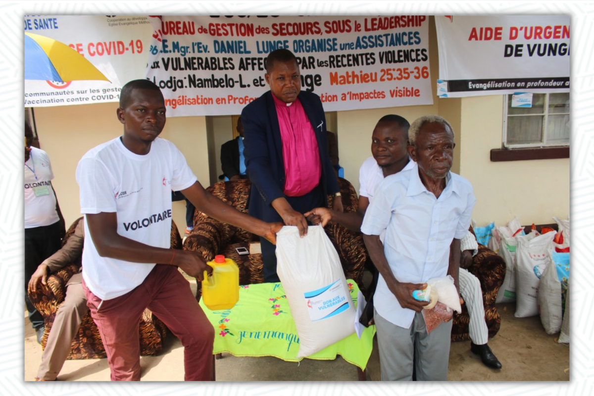 The Bishop Daniel Lunge assisted by UMCOR volunteers including Armand Osango and Placide gave the bag of rice to Papa Jean Okito, one of the victims. The Church brought food to displaced people who fled clashes between two communities following a forest conflict. Photo by Francois Omanyondo, UM News.