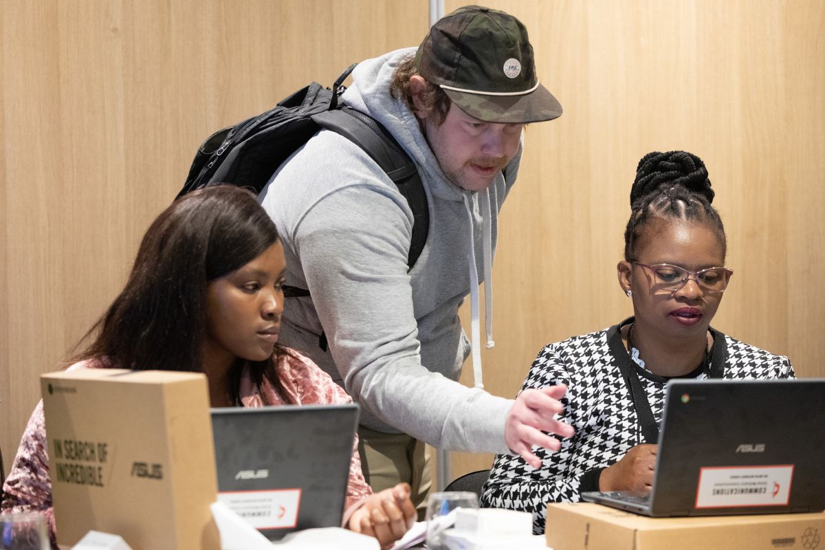 Matt Crum with the Global Communication Technology team helps communicators Zizipho Qata and Bulelwa Ndedwa with their Chromebooks during training in Cape Town, South Africa. (Photo by Mike DuBose, UM News.)