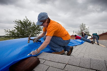 Kaci Underwood works to fasten down a tarp over a tornado-damaged roof in advance of a brewing storm in Moore, Okla. Underwood was part of a volunteer team working out of First United Methodist Church in Moore. Photo by Mike DuBose, UMNS.