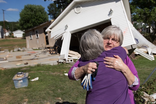 Marsha Fogus (right) is comforted by the Rev. Melissa Shortridge at her home in White Sulphur Springs, W. Va. Fogus’ garage was moved off its foundation and her home was heavily damaged by floodwaters. Photo by Mike DuBose, UMNS.