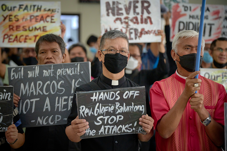 At a Sept. 21 memorial service marking the 50th anniversary of martial law in the Philippines, Bishop Ciriaco Francisco, the resident bishop of the Manila Area, holds a sign supporting the Rev. Glofie Baluntong, a United Methodist pastor who has been charged with attempted murder in a case she and her supporters believe was invented to intimidate her. Photo © Paul Jeffrey, Life on Earth Pictures.