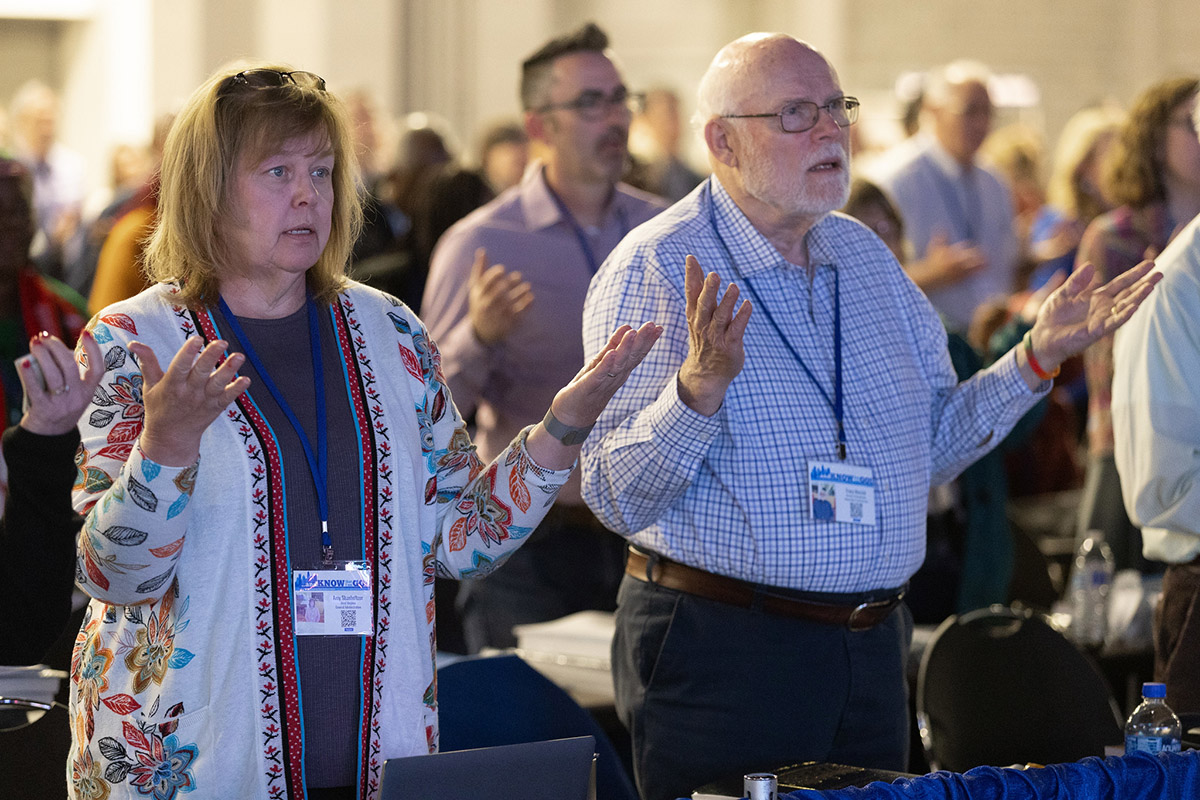 The Rev. Amy Shanholtzer of the West Virginia Conference and Tracy Merrick of the Western Pennsylvania Conference pray during opening worship at the 2024 United Methodist General Conference in Charlotte, N.C. Photo by Mike DuBose, UM News.