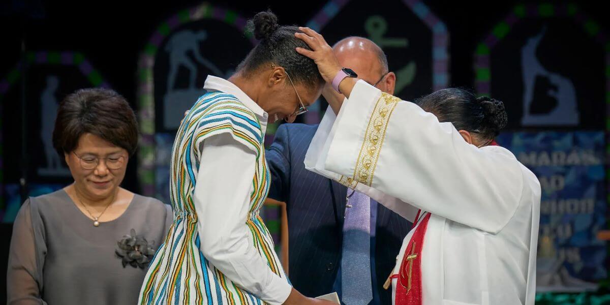 Bishop Ruby-Nell M. Estrella commissions Mamei Sombo Lansana as a missionary during the May 2 morning worship of the 2024 United Methodist General Conference in Charlotte, N.C. Assisting are Grace Choi and Roland Fernandes. (Photo: Paul Jeffrey/UM News)