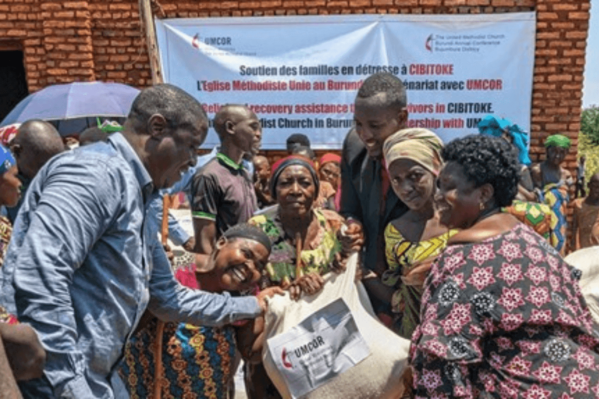 Patrick Abro (left), a United Methodist missionary serving as health operation manager in the Burundi Conference, and the Rev. Cimpaye Valentine (right), Bujumbura District superintendent, hand a bag of rice to flood survivors in Cibitoke, Burundi. With financial support from the United Methodist Committee on Relief, the church helped 140 households affected by severe flooding in the district. Photo by Jérôme Ndayisenga, UM News.