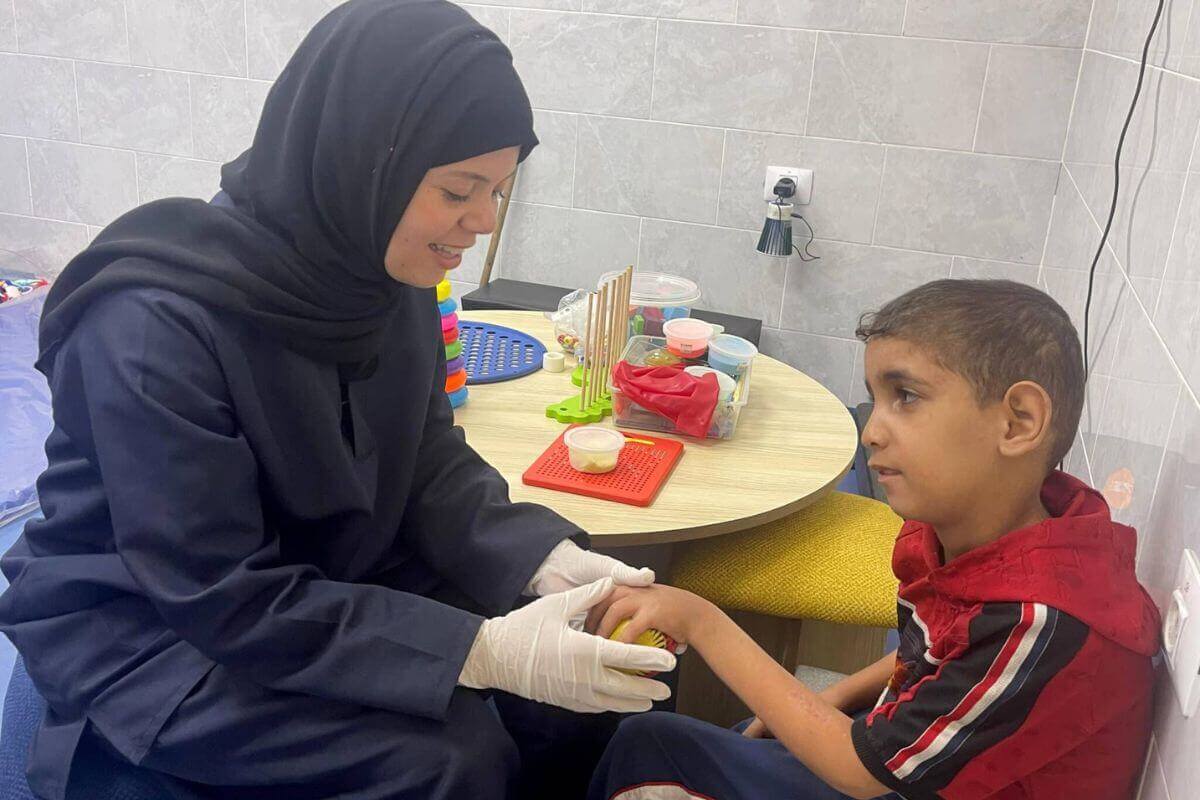 A caregiver in the Princess Basma Centre Satellite in Gaza gives treatment to a child whose family had to stay in Gaza City. Photo courtesy of Princess Basma Centre.