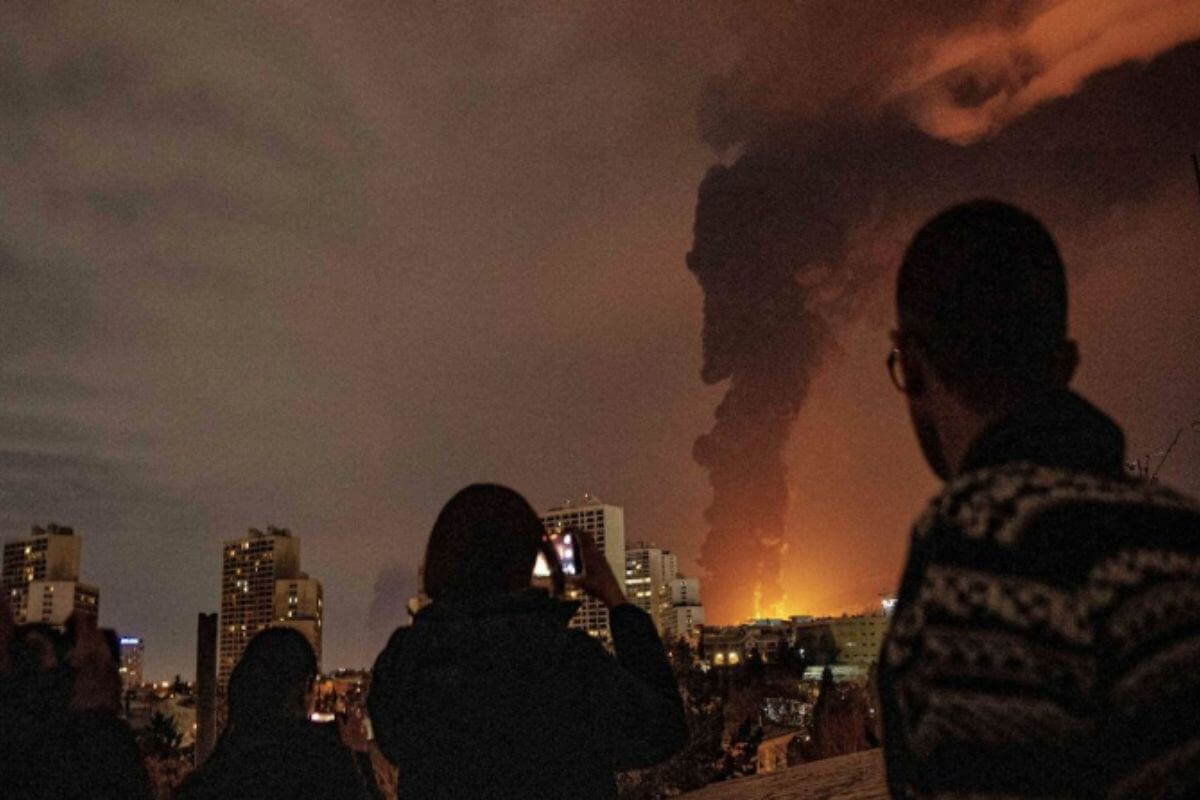 Iranian residents take pictures as flames and smoke rise from U.S. missile attack on an oil storage facility in Tehran, Iran, Saturday, March 7, 2025. (photo credit: Alireza Sotabar/ISNA via AP)
