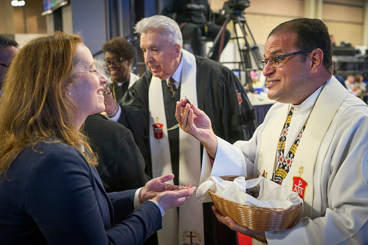Bishop Héctor A. Burgos Núñez, who leads the Upper New York and Susquehanna conferences, distributes communion to participants during opening worship service on April 23, 2024, at General Conference in Charlotte, N.C. Next to him, also distributing communion, is Horizon Texas Conference Ruben Saenz Jr., who is now the Council of Bishops president. A United Methodist leadership body recommends that the U.S. have 34 bishops starting in 2028. File photo by Paul Jeffrey, UM News. 