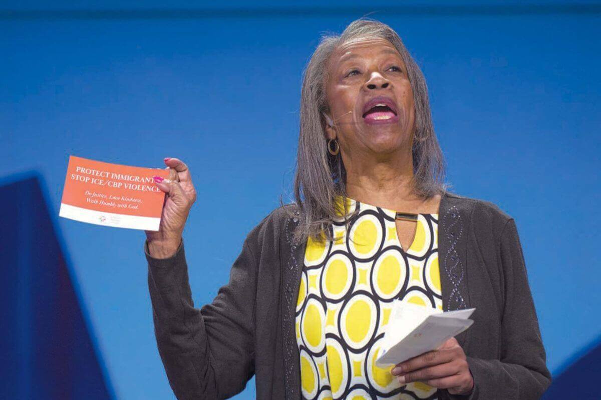 Roxie Hutsell of the West Ohio Conference holds up a postcard on May 17, 2026, asking participants in the United Women in Faith Assembly in Indianapolis to fill it out and send it to Congress demanding an end to government-sponsored violence against immigrants. Photo courtesy of Paul Jeffrey.
