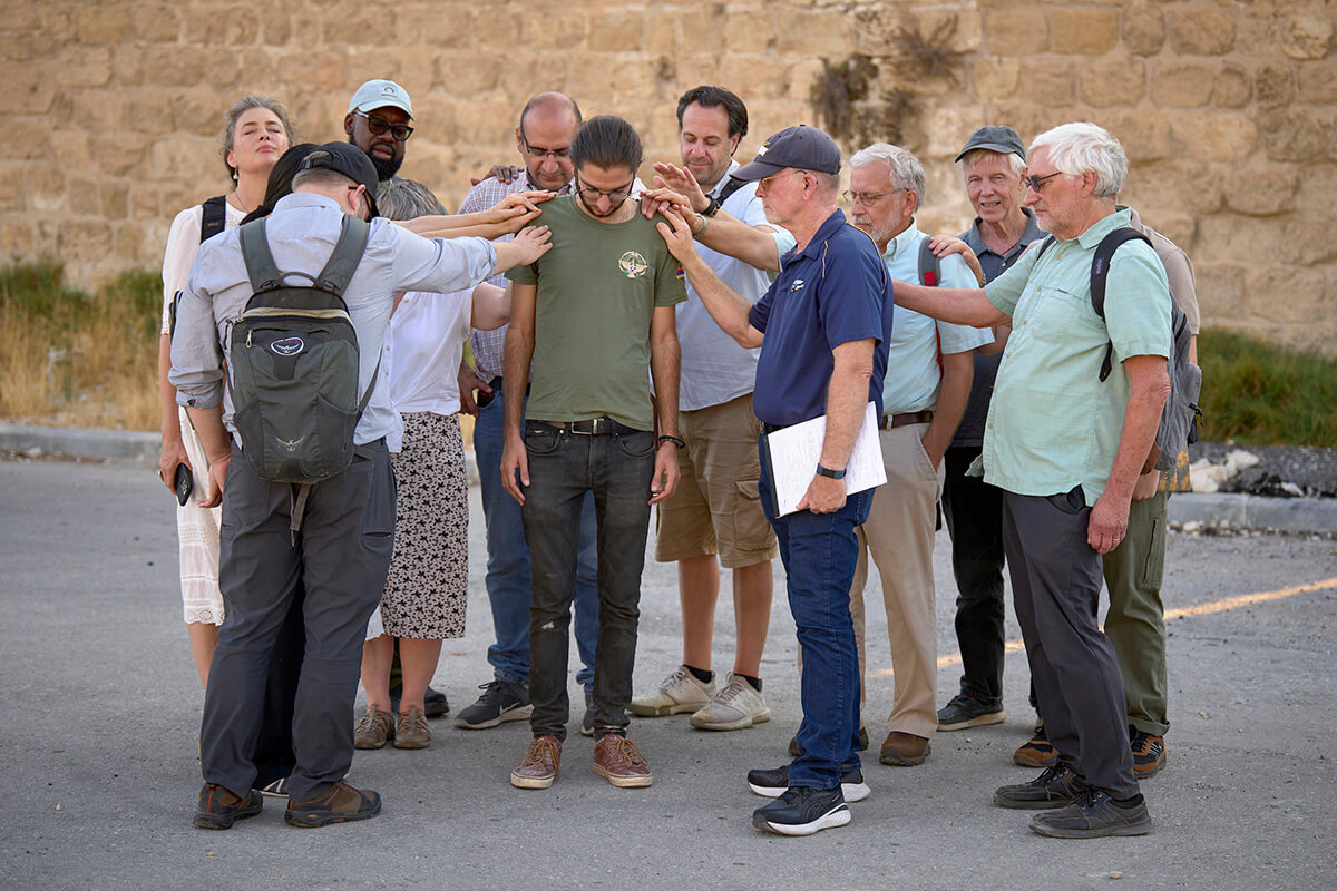 In this 2024 file photo, a visiting delegation of church activists from the United States prays for Setrag Balian (center), a leader of the youth-led struggle to save the Armenian Quarter of Jerusalem's Old City. The delegation came to the Middle East to accompany threatened Christians and other Palestinians and call for a ceasefire in Gaza. A similar U.S. interfaith delegation traveling to Israel and Palestine to meet with Christians in the Holy Land was turned away at the Israel border on Aug. 13. The group included four United Methodists. File photo by Paul Jeffrey, Life on Earth Pictures.