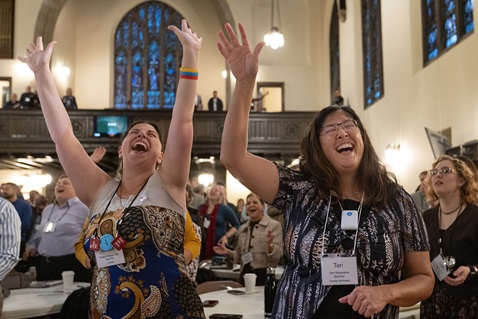 Ashlee Vitz (left) and Teri Watanabe raise their arms in praise during opening worship Oct. 21 at the United Methodist Leadership Gathering at Knox United Church in Calgary, Canada. The event, which continues through Oct. 24, brings lay and clergy from around the world together to imagine a new future for The United Methodist Church. Photo by Mike DuBose, UM News.
