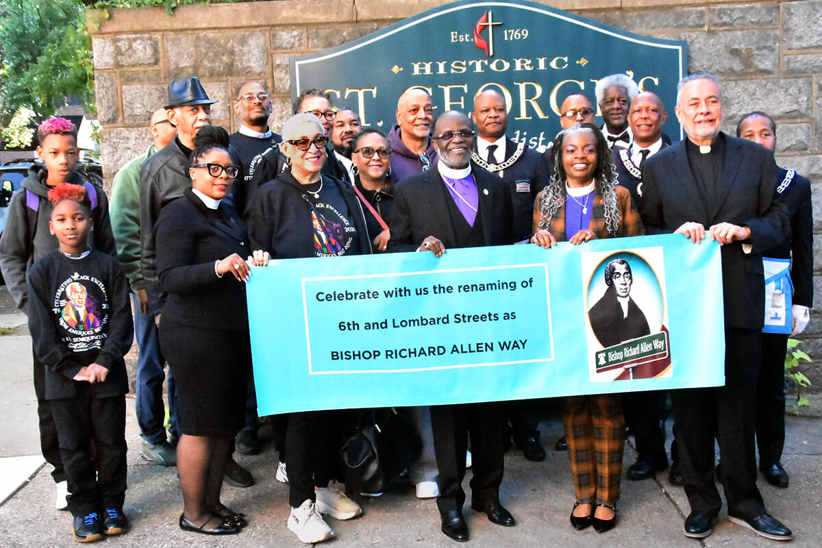 Holding a banner for the Bishop Richard Allen Way street renaming celebration Oct. 7 at Historic St. George’s United Methodist Church in Philadelphia are (from left): the Rev. Carolyn Cavaness, pastor of Mother Bethel African Methodist Episcopal  Church; Yvonne Studevan, an Allen descendant; AME Bishop Samuel Lawrence Green Sr.; United Methodist Bishop Cynthia Moore-Koikoi; and the Rev. William Wilson Sr., pastor of St. George’s. Surrounding them are other descendants and members of the Prince Hall Masons lodge named for Bishop Allen. Photo by John W. Coleman, UM News. 
